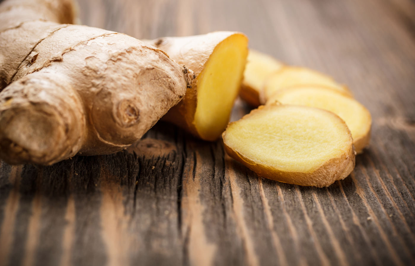 Fresh ginger with thick cut slices on a wooden table