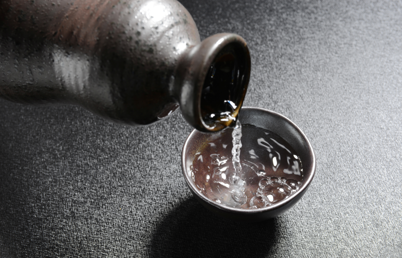 Shochu being poured from a traditional Japanese Tokkuri into an Ochoko sake cup